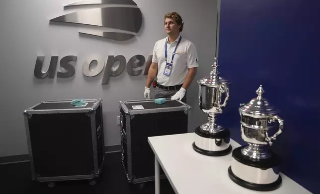 Aidan Hawkesworth, U.S. Open player operations team member, stands to the side as the women's keepsake, left, and presentation trophies are photographed during the U.S. Open tennis championships, Wednesday, Sept. 3, 2025, in New York. (AP Photo/Kirsty Wigglesworth)