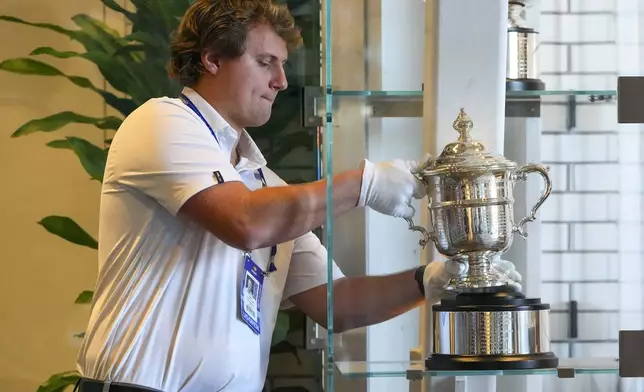 Aidan Hawkesworth, U.S. Open player operations team member, places the women's presentation trophy in a display case during the U.S. Open tennis championships, Wednesday, Sept. 3, 2025, in New York. (AP Photo/Kirsty Wigglesworth)