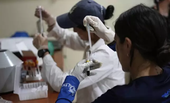 Scientists examine blood samples that were drawn from pink river dolphins in the Amazon River to determine mercury levels in Puerto Narino, Colombia, Sunday, Sept. 7, 2025. (AP Photo/Fernando Vergara)
