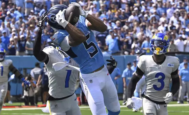 Tennessee Titans wide receiver Elic Ayomanor (5) catches a pass for a touchdown as Los Angeles Rams cornerback Emmanuel Forbes Jr. (1) and safety Kam Curl (3) defend during the first half of an NFL football game Sunday, Sept. 14, 2025, in Nashville, Tenn. (AP Photo/John Amis)