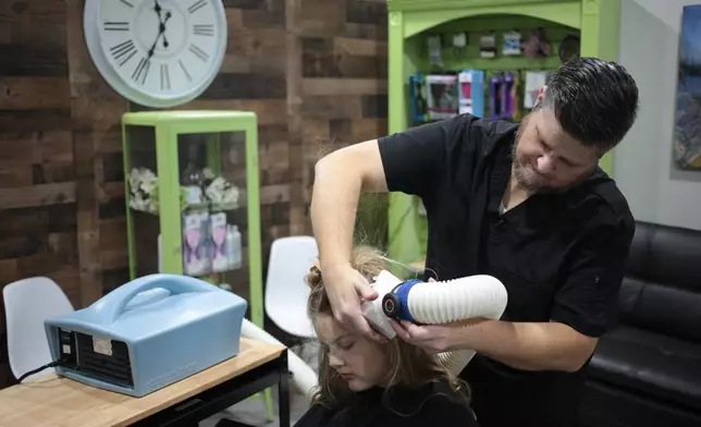 Jacob Anthon demonstrates the use of an FDA-cleared device that uses a combination of airflow temperature, speed, and direction to kill lice and eggs at Lice Clinics of America in Sugar Land, Texas, Monday, Sept. 22, 2025. (AP Photo/Lekan Oyekanmi)