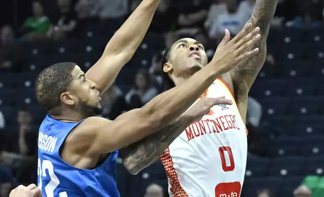 Britain's Myles Hesson, left, and Montenegro's Nikola Vucevic, right, challenge for the ball during the Eurobasket, European Basketball Championship, group B match between Montenegro and Great Britain in Tampere, Finland, Wednesday, Sept. 3, 2025. (Heikki Saukkomaa/Lehtikuva via AP)
