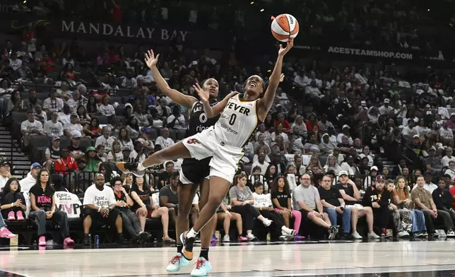 Indiana Fever guard Kelsey Mitchell, right, shoots against Las Vegas Aces guard Jackie Young, left, in the second half of Game 1 of a WNBA basketball playoff semifinals series Sunday, Sept. 21, 2025, in Las Vegas. (AP Photo/Candice Ward)