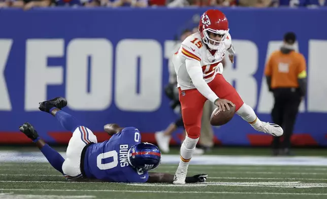 Kansas City Chiefs quarterback Patrick Mahomes (15) scrambles away from New York Giants outside linebacker Brian Burns (0) during the first half of an NFL football game Sunday, Sept. 21, 2025, in East Rutherford, N.J. (AP Photo/Adam Hunger)