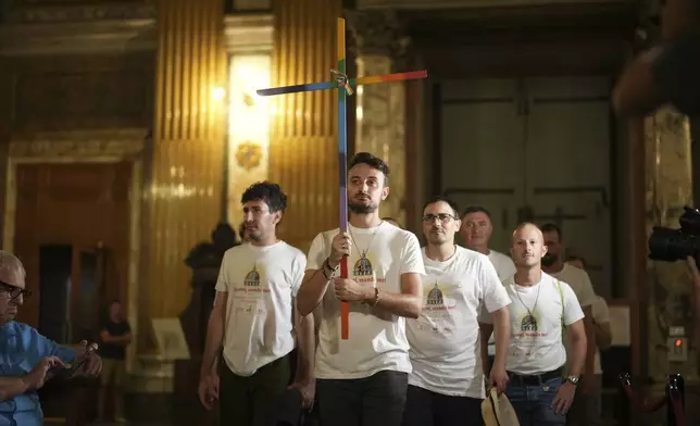Andrea Mattei, holding a cross arrives with other members of the LGBTQ+ community to attend a vigil prayer in the Church of the Gesu' in central Rome, Friday, Sept. 5, 2025. (AP Photo/Andrew Medichini)