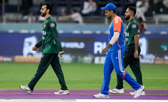 Pakistan's captain Salman Agha, left, and India's captain Suryakumar Yadav, center, walk out on to the field for the national anthems before the Asia Cup cricket final between India and Pakistan at Dubai International Cricket Stadium, United Arab Emirates, Sunday, Sept. 28, 2025. (AP Photo/Altaf Qadri)