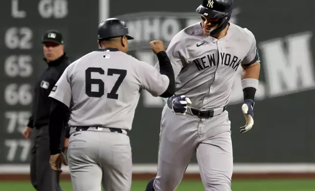 New York Yankees designated hitter Aaron Judge, right, fist-bumps third base coach Luis Rojas (67) after hitting a home run during the first inning of a baseball game against the Boston Red Sox, Friday, Sept. 12, 2025, in Boston. (AP Photo/Mark Stockwell)