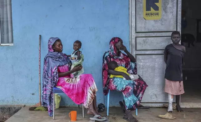Patients sit outside the malnutrition ward of Bunj Hospital in Maban, South Sudan, Tuesday, Aug. 19, 2025. (AP Photo/Caitlin Kelly)