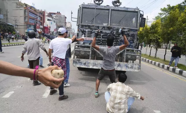 Protesters shout slogans in front of an armored vehicle outside the Parliament building in Kathmandu, Nepal, Monday, Sept. 8, 2025. (AP Photo/Niranjan Shrestha)