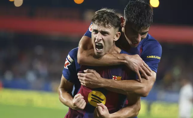 Barcelona's Fermin Lopez celebrates scoring his side's 3rd goal with teammate Gerard Martin during a Spanish La Liga soccer match between FC Barcelona and Valencia at the Johan Cruyff stadium in Barcelona, Spain, Sunday, Sept. 14, 2025. (AP Photo/Joan Monfort)