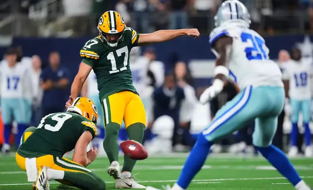 Green Bay Packers' Brandon McManus (17) kicks a game-tying fielg goal with Daniel Whelan (19) holding in the second half of an NFL football game against the Dallas Cowboys Sunday, Sept. 28, 2025, in Arlington, Texas. (AP Photo/Julio Cortez)