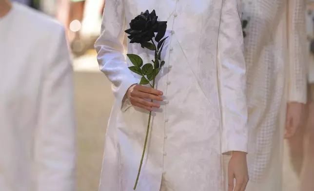 A model wears a creation as part of the Francesca Liberatore Spring/Summer 2026 collection as she holds a black rose, in Milan, Italy, Sunday, Sept. 28, 2025. (AP Photo/Antonio Calanni)