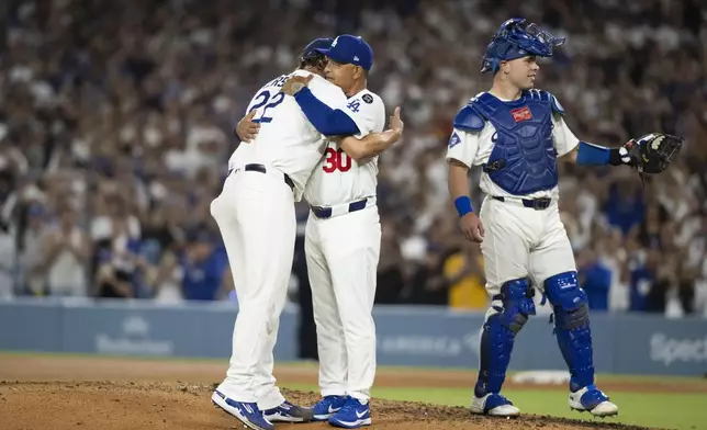 Los Angeles Dodgers starting pitcher Clayton Kershaw, left, hugs manager Dave Roberts, center, after being removed during the fifth inning of a baseball game against the San Francisco Giants, in Los Angeles, Friday, Sept. 19, 2025. (AP Photo/Kyusung Gong)