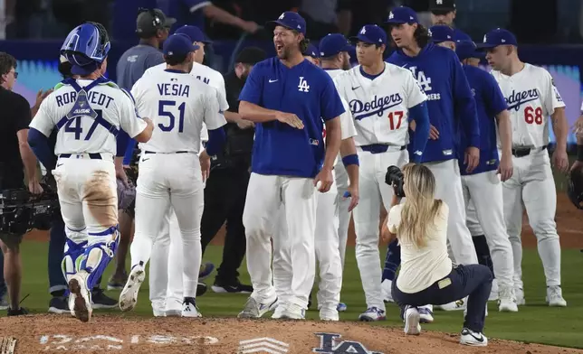 Los Angeles Dodgers' Clayton Kershaw, center, congratulates members of his team after the Dodgers defeated the San Francisco Giants in a baseball game Thursday, Sept. 18, 2025, in Los Angeles. (AP Photo/Mark J. Terrill)