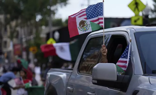 Participants wave flags as they take part in the 2025 Pilsen Mexican Independence Day parade Saturday, Sept. 6, 2025, in Chicago. (AP Photo/Carolyn Kaster)