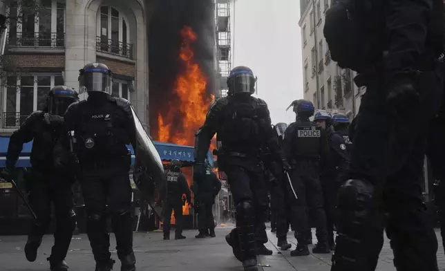Riot police officers take position in front of a burning restaurant during the « Bloquons Tout » (Block Everything) protest movement in Paris, France, Wednesday, Sept. 10, 2025. (AP Photo/Thibault Camus)