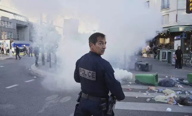 A police officer stands next to bins placed on a street to block it during the "Bloquons Tout" (Block Everything) protest movement in Paris, Wednesday, Sept. 10, 2025. (AP Photo/Thibault Camus)