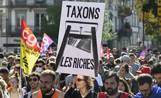 A protester holds a placard that reads, "let's tax the rich," during a rally of the "Block Everything" movement in Strasbourg, eastern France, Wednesday, Sept. 10, 2025. (AP Photo/Pascal Bastien)