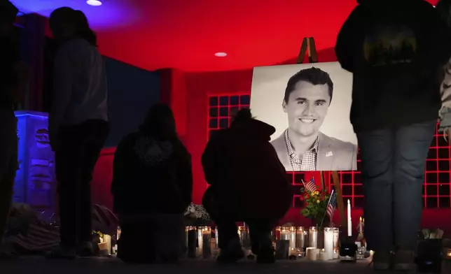 People place lit candles below a photo of Charlie Kirk, the CEO and co-founder of Turning Point USA who was shot and killed, at a vigil in his memory, Thursday, Sept. 11, 2025, in Orem, Utah. (AP Photo/Lindsey Wasson)