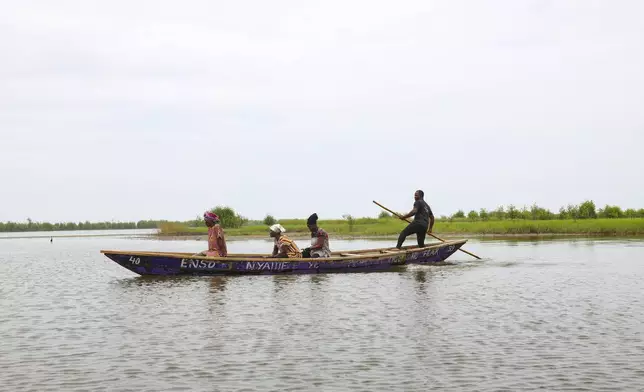 Women head out on a boat to harvest oysters at Tsokomey, Ghana, Aug. 6, 2025. (AP Photo/Misper Apawu)