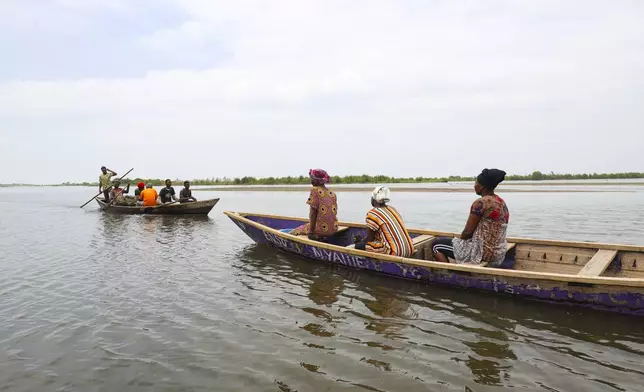 Women leave on boats to harvest oysters at Tsokomey, Ghana, Aug. 6, 2025. (AP Photo/Misper Apawu)