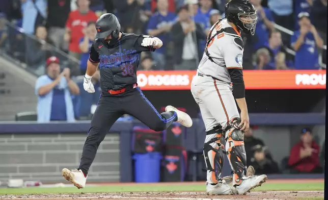 Toronto Blue Jays' Davis Schneider (36) scores as Baltimore Orioles catcher Samuel Basallo (29) looks on during fifth inning MLB baseball action in Toronto, Friday Sept. 12, 2025. (Chris Young/The Canadian Press via AP)