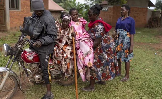 Deziranta Namisango, second from left, who has dementia, sits on a motorcycle taxi as Christine Nababi, 80, is helped onto the seat by NGO field officer, Elizabeth Nagawa, as they leave their biweekly fellowship gathering for seniors at a church in Mukono, Uganda, Thursday, Nov. 14, 2024. (AP Photo/David Goldman)