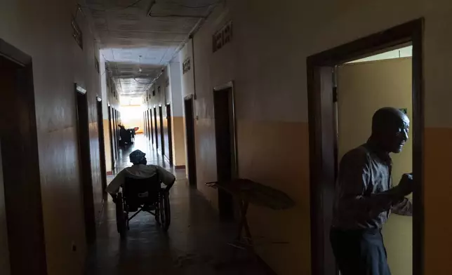 Residents return to their rooms at a home for seniors, disabled and abandoned people run by the Good Samaritan Sisters of Nalukolongo, one of the few care facilities for seniors in the country, in Kampala, Uganda, Saturday, Nov. 23, 2024. (AP Photo/David Goldman)