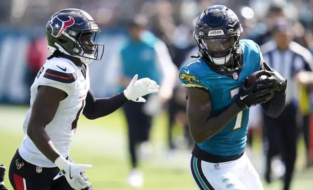 Jacksonville Jaguars wide receiver Brian Thomas Jr., right, holds the ball after making a catch as Houston Texans cornerback Kamari Lassiter tries to push him out of bounds during the second half of an NFL football game Sunday, Sept. 21, 2025, in Jacksonville, Fla. (AP Photo/John Raoux)