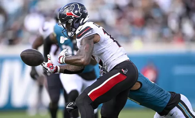 Houston Texans wide receiver Nico Collins, front, fumbles the ball after taking a hit from Jacksonville Jaguars cornerback Tyson Campbell during the second half of an NFL football game Sunday, Sept. 21, 2025, in Jacksonville, Fla. (AP Photo/Phelan M. Ebenhack)