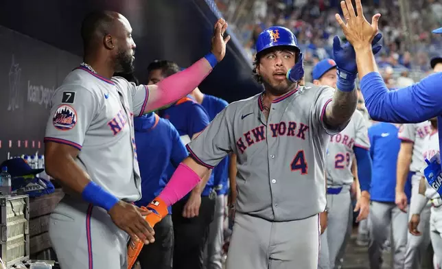 New York Mets' Francisco Alvarez (4) is congratulated in the dugout after scoring on a RBI single hit by Francisco Lindor during the ninth inning of a baseball game, Saturday, Sept. 27, 2025, in Miami. (AP Photo/Lynne Sladky)