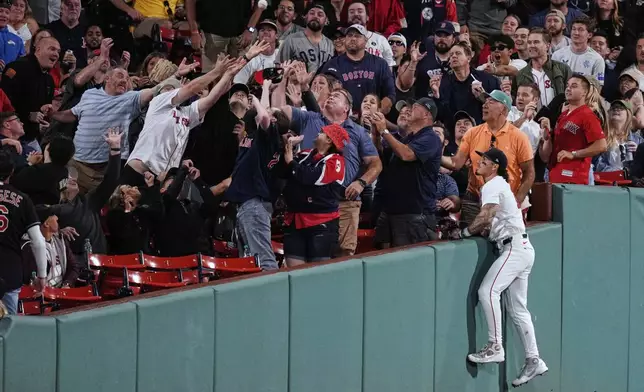 Boston Red Sox outfielder Jarren Duran, right, watches as fans try to make a catch on a foul ball by Cleveland Guardians' Steven Kwan during the fifth inning of a baseball game at Fenway Park, Wednesday, Sept. 3, 2025, in Boston. (AP Photo/Charles Krupa)