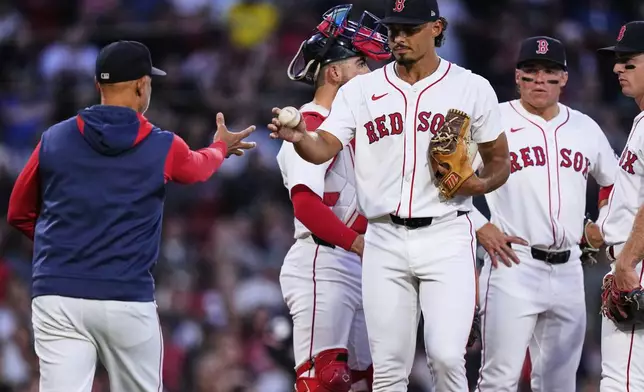 Boston Red Sox pitcher Jordan Hicks, center right, gives the ball to manager Alex Cora while getting pulled in the second inning of a baseball game against the Cleveland Guardians at Fenway Park, Wednesday, Sept. 3, 2025, in Boston. (AP Photo/Charles Krupa)