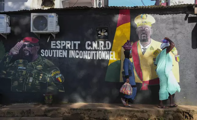 People walk past a mural showing Guinea's interim president, Col. Mamadi Doumbouya, ahead of the constitutional referendum in Conakry, Guinea, Wednesday, Sept. 17, 2025. (AP Photo/Misper Apawu)