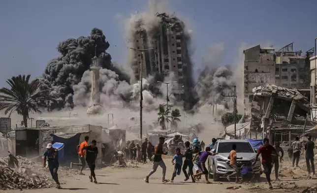 Palestinians run for cover during an Israeli airstrike on a high-rise building in Gaza City, Friday, Sept. 5, 2025, after the Israeli army issued a prior warning. (AP Photo/Yousef Al Zanoun)