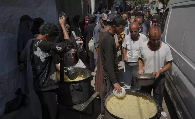 Palestinians line up to receive donated food at a community kitchen in Deir al-Balah, southern Gaza Strip, Saturday, Sept. 6, 2025. (AP Photo/Jehad Alshrafi)