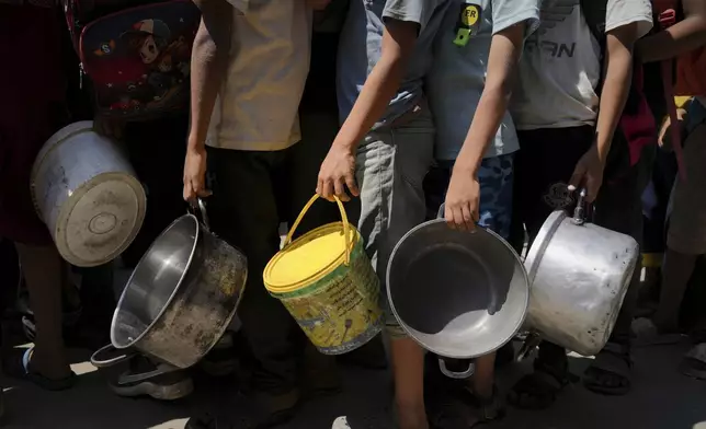 Palestinians line up to receive donated food at a community kitchen in Deir al-Balah, southern Gaza Strip, Saturday, Sept. 6, 2025. (AP Photo/Jehad Alshrafi)