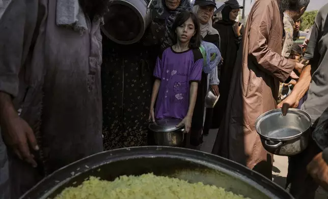 Palestinians line up to receive donated food at a community kitchen in Deir al-Balah, southern Gaza Strip, Saturday, Sept. 6, 2025. (AP Photo/Jehad Alshrafi)