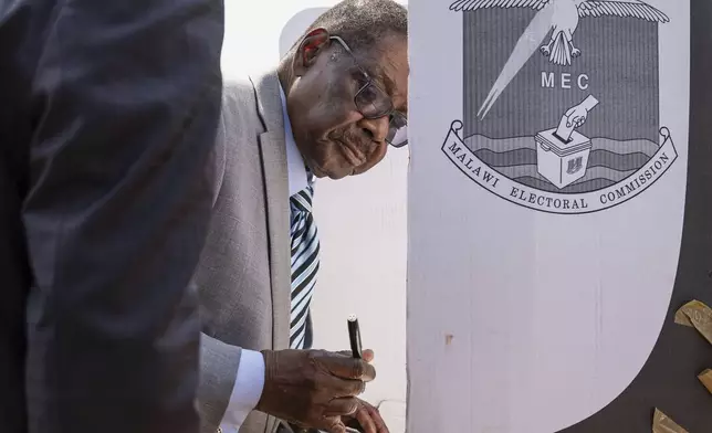 Malawi's presidential candidate, former President Peter Mutharika stands on a voting booth as he prepares to cast his vote in Thyolo District, Malawi, Tuesday, Sept. 16, 2025. (AP Photo/Thoko Chikondi)