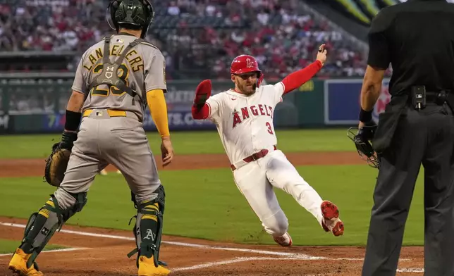 Los Angeles Angels' Taylor Ward,, center, scores on a single by Oswald Peraza as Athletics catcher Shea Langeliers stands by during the first inning of a baseball game Friday, Sept. 5, 2025, in Anaheim, Calif. (AP Photo/Mark J. Terrill)