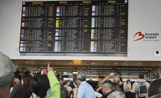 An airport employee points at a departure board after a cyber attack caused delays at Brussels International Airport in Zaventem, Belgium, Saturday, Sept. 20, 2025. (AP Photo/Harry Nakos)