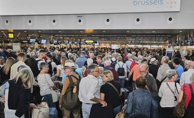 People stand in a line to check in after a cyber attack caused delays at Brussels International Airport in Zaventem, Belgium, Saturday, Sept. 20, 2025. (AP Photo/Harry Nakos)