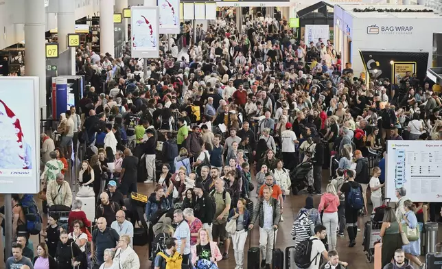People walk by a departures board after a cyber attack caused delays at Brussels International Airport in Zaventem, Belgium, Saturday, Sept. 20, 2025. (AP Photo/Harry Nakos)