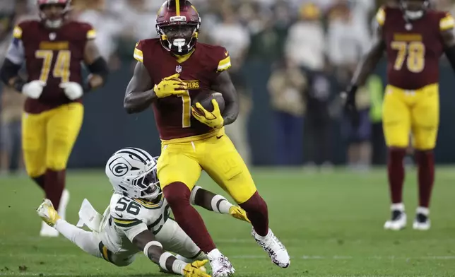 Washington Commanders wide receiver Deebo Samuel (1) catches the ball and runs for a first down as Green Bay Packers linebacker Edgerrin Cooper (56) defends during the second half of an NFL football game Thursday, Sept. 11, 2025, in Green Bay, Wis. (AP Photo/Matt Ludtke)