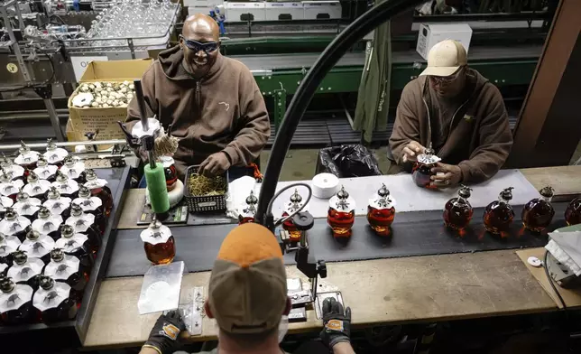 Workers process freshly filled bottles of Blanton's bourbon in a bottling area at Buffalo Trace Distillery on Sept. 16, 2025, in Frankfort, Ky. (AP Photo/Jon Cherry)