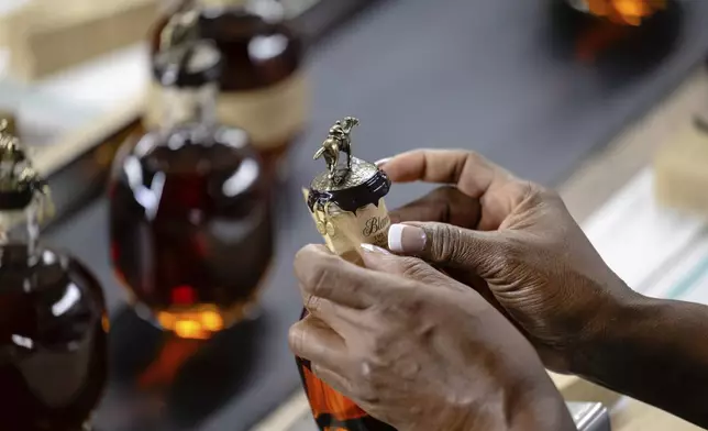 A worker places part of an ornate seal on a bottle of Blanton's bourbon in a bottling area at Buffalo Trace Distillery on Sept. 16, 2025, in Frankfort, Ky. (AP Photo/Jon Cherry)