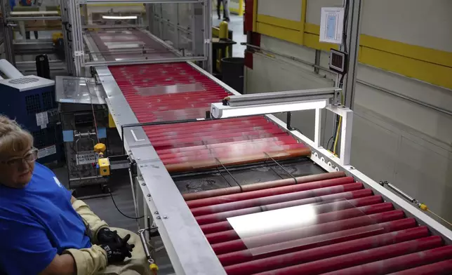 A quality control employee looks on as lengths of glass move down the line during a tour of Corning's iPhone glass manufacturing facility Friday, Sept. 12, 2025, in Harrodsburg, Ky. (AP Photo/Jon Cherry)