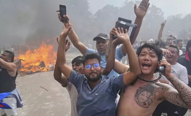 Protesters celebrate at the Singha Durbar, the seat of Nepal's government's various ministries and offices, after burning it down during a protest against a social media ban and corruption in Kathmandu, Nepal, Tuesday, Sept. 9, 2025. (AP Photo/Niranjan Shrestha)