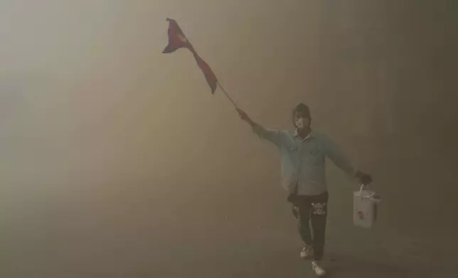 A protester celebrates at the Singha Durbar, the seat of Nepal's government's various ministries and offices, after it was set on fire during a protest against social media ban and corruption in Kathmandu, Nepal, Tuesday, Sept. 9, 2025. (AP Photo/Niranjan Shrestha)