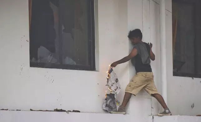 A protester tries to burn Nepalese congress party central office during protests against social media ban and corruption in Kathmandu, Nepal, Tuesday, Sept. 9, 2025. (AP Photo/Niranjan Shrestha)